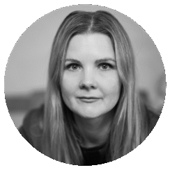 Black and white portrait of Ailsa Paterson, a woman with long, straight hair, looking directly at the camera with a neutral expression. The photo is framed in a circular shape.