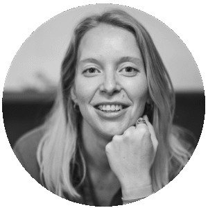 Black-and-white portrait of Georgia Stanley, a smiling woman with long light hair, resting her chin on her hand and looking at the camera.