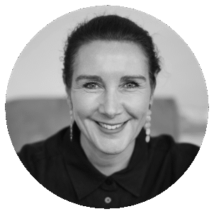 Black and white portrait of Rebecca Pearce, a woman with dark hair pulled back, wearing earrings and a collared shirt, smiling warmly while looking directly at the camera.