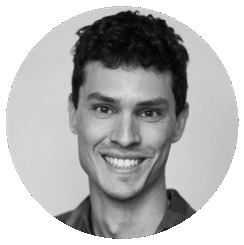 A black and white portrait of Darian Tregenza, a smiling young man with short, curly hair, wearing a collared shirt, facing the camera against a plain background.