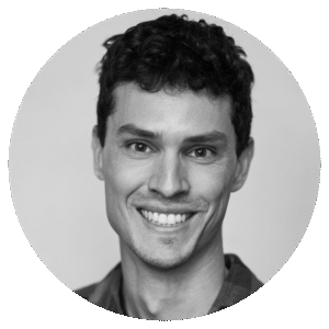 A black and white portrait of Darian Tregenza, a smiling young man with short, curly hair, wearing a collared shirt, facing the camera against a plain background.