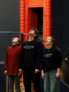 Three actors stand side by side looking upwards