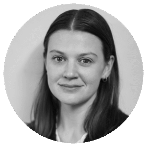 Black and white portrait of a young woman with straight, dark hair, wearing small hoop earrings and a light-colored top, looking directly at the camera with a neutral expression.